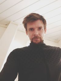 Portrait of young man standing at home