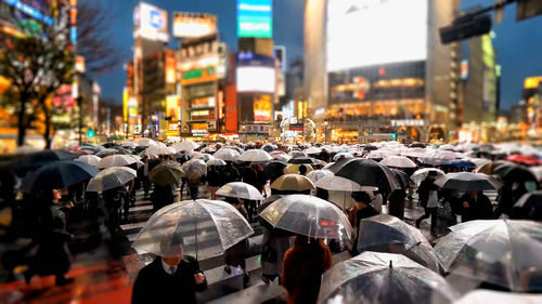 Rear view of people with umbrella walking on street in city