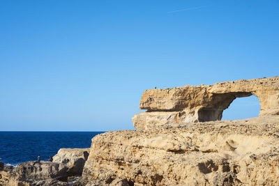 Cliff by sea against clear sky at gozo island