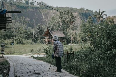 Rear view of person walking on footpath during rainy season