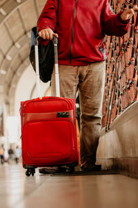 Low section of man with red suitcase at airport