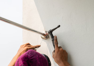 Worker welding stainless steel pipe clothesline in building.