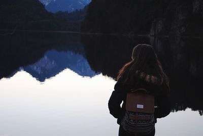 Woman standing by lake against sky