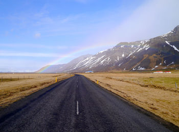 Road by mountains against blue sky