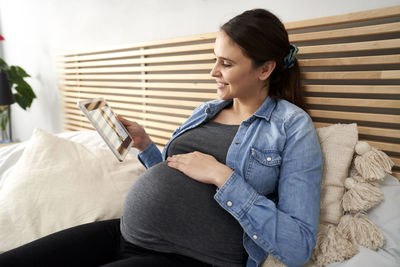 Pregnant woman using tablet pc at home