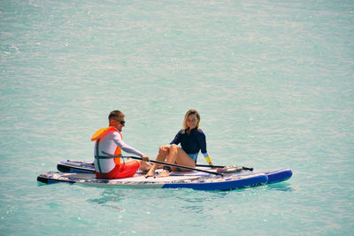 Man and woman sitting on a stand up paddle boards. couple taking time together relaxing on sup board