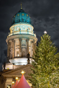 Low angle view of illuminated christmas tree against french cathedral at night