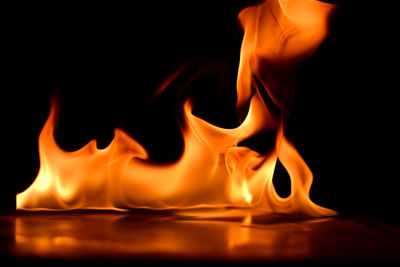 Close-up of burning candle against black background