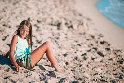 Portrait of young woman sitting on sand at beach