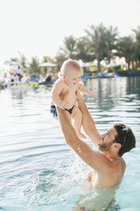 Father playing with baby in swimming-pool