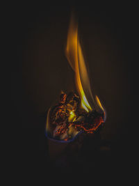 Close-up of burning candle against black background