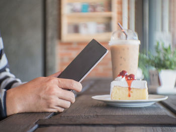 Close-up of hand holding ice cream cone on table
