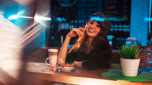 Portrait of young woman sitting at restaurant table