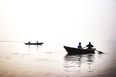 People on boat in sea against sky