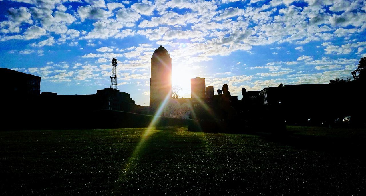 architecture, built structure, building exterior, lens flare, sunbeam, sunlight, sun, sky, silhouette, city, outdoors, cloud - sky, grass, skyscraper, travel destinations, field, no people, day, nature, modern, cityscape