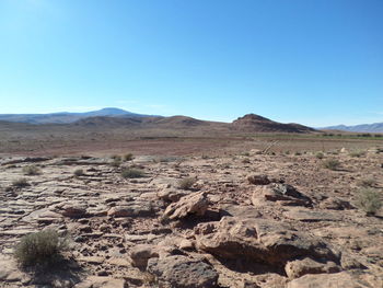 Scenic view of arid landscape against clear blue sky