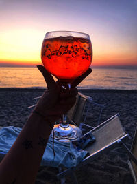 Close-up of hand holding drink at sunset
