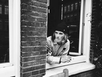 Young man smoking cigarette at window