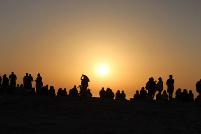 Silhouette people on beach against sky during sunset