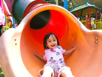 Portrait of cute girl playing on slide in playground