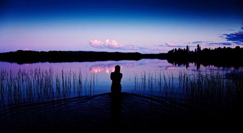 Rear view of woman overlooking calm lake