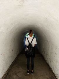 Rear view of woman standing in tunnel