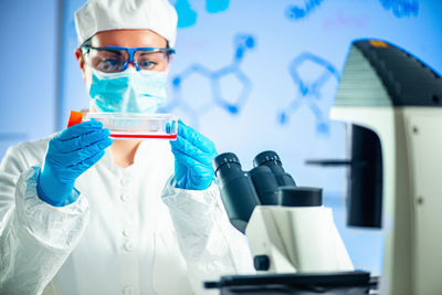 Close-up of scientist holding laboratory glassware while doing experiment in laboratory