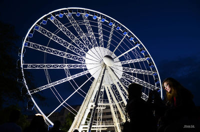 Low angle view of illuminated ferris wheel against sky at night