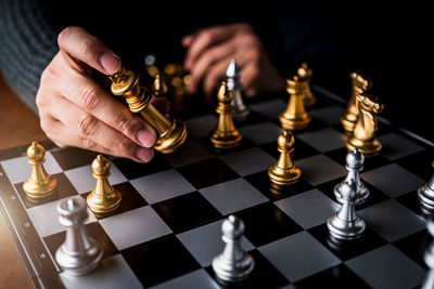 Cropped hands of person holding chess piece on board