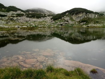 Scenic view of lake by mountain against sky