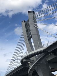 Low angle view of suspension bridge against cloudy sky