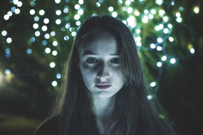 Close-up portrait of teenage girl against defocused lights