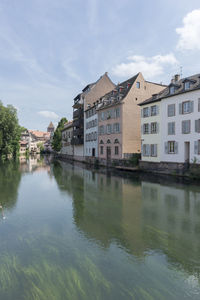 Houses by river in city against sky