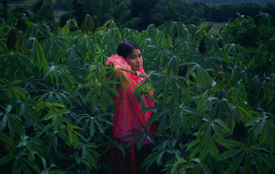 Woman wearing raincoat standing amidst plants