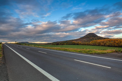 Empty road by mountains against sky