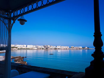 Boats moored in sea against clear blue sky