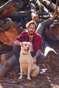 Portrait of young tattoed man with his dog in the forest