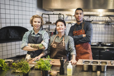 Portrait of confident chefs standing at kitchen counter in restaurant