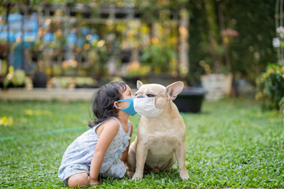 Little girl and her french bulldog wearing medical mask prevent pollution, flu and convid19 at park.
