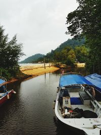 Boats moored on lake against sky