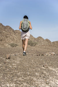 Portrait of man standing on rock against sky
