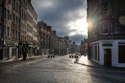 Street amidst buildings against sky during sunset