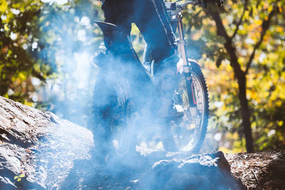 Low section of man riding motorcycle at forest