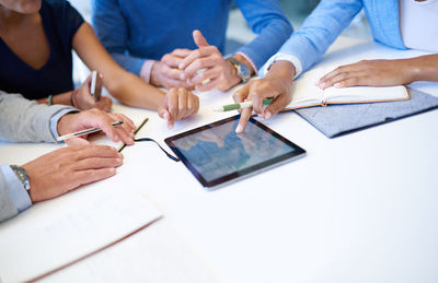 Midsection of real estate agent giving key to colleague in office