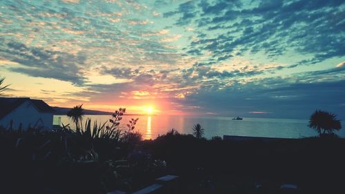 Scenic view of sea against cloudy sky during sunset