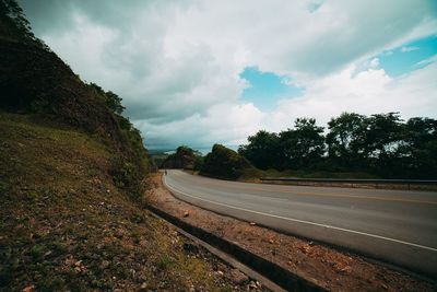 Road by trees against sky