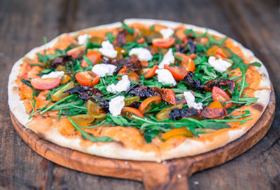 Big vegetable pizza on the wooden board with cheese and tomatos