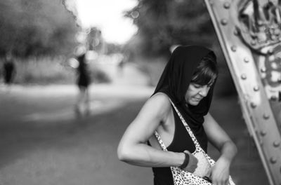 Woman looking in purse while standing on field