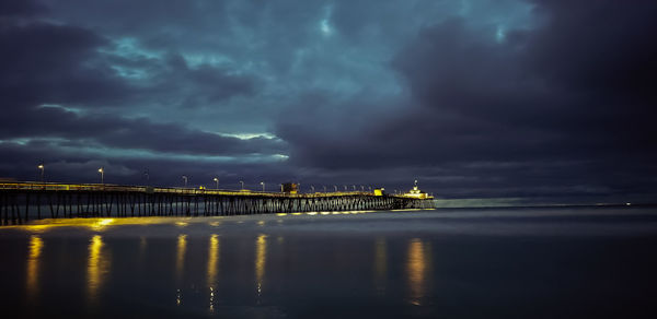 Bridge over sea against storm clouds