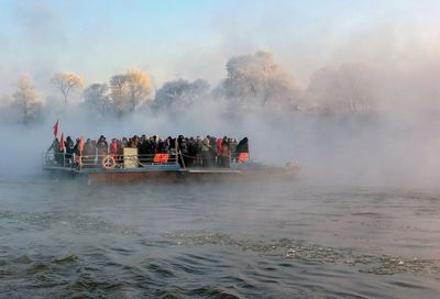 People on boat in lake during foggy weather